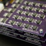 stacked purple circuit boards with grid of electronic components